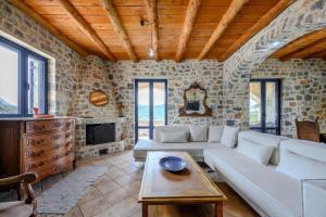 a living room with a white couch and a stone wall at Petritis in Lambiní