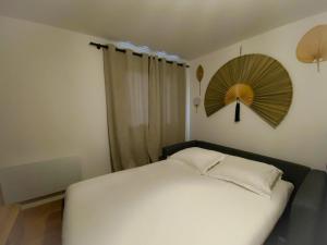 1 dormitorio con 1 cama blanca y ventilador en la pared en Le Côte d'Opale en Calais