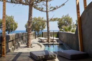 a swimming pool with two ottomans on a wooden walkway at Oscar Beachfront Suites in Perivolos