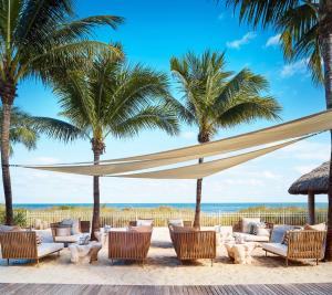 uma praia com cadeiras e guarda-sóis e palmeiras em Lovely Deluxe Unit Located at Ritz Carlton - Key Biscayne! em Miami