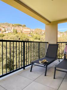une chaise noire sur un balcon avec vue dans l'établissement Villa entre Rose et Pins à Bormes-les-mimosas 4 étoiles - ROSES&PINS, à Bormes-les-Mimosas
