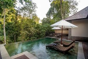 a swimming pool with two chairs and an umbrella at The Lokha Ubud Resort, Villas & SPA in Ubud