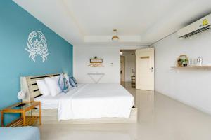 a bedroom with a white bed and a blue wall at Turtle Rooms in Bang Tao Beach