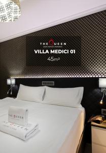 uma cama num quarto de hotel com uma placa na parede em The Queen Luxury Apartments - Villa Medici no Luxemburgo