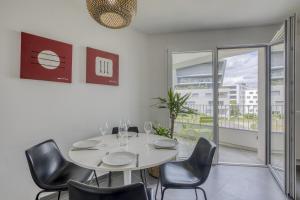 une salle à manger avec une table blanche et des chaises noires dans l'établissement View Point City, à Annecy