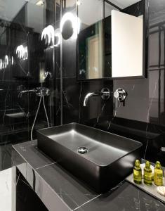 a black bathroom with a sink and a mirror at Dion Luxury Suites in Athens +72 photos