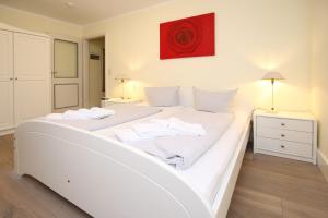 un letto bianco in una camera da letto con un dipinto rosso sul muro di Am Gruenstreifen 33_ Whg_ 8 _Klein a Wyk auf Föhr