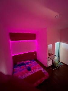 KalakにあるPlatar Ombo Homestayのベッドルーム1室(ピンクの照明が付いたベッド1台付)