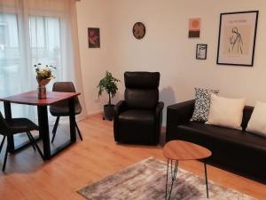 sala de estar con sofá negro y mesa en Premium Apartment mit Terrasse en Wörth