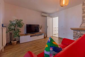 een woonkamer met een rode bank en een flatscreen-tv bij Casa Kiwi in Premantura