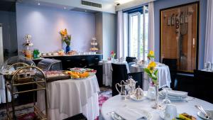 une salle à manger avec des tables et des nappes blanches dans l'établissement Hotel Villa Cansignorio, à Lazise