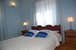 a bedroom with a white bed with blue pillows at Villa Korakades in Korakádes