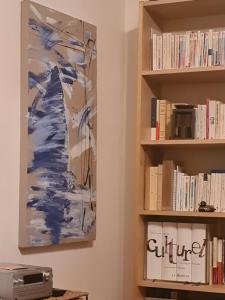 ein Gemälde, das an einer Wand neben einem Bücherregal hängt in der Unterkunft Appartement à Montmartre in Paris