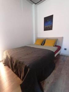 a bedroom with a large bed with yellow pillows at Erdvi studija Spacious studio apartment Self check in in Vilnius