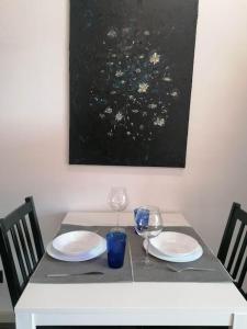 a table with two plates and wine glasses on it at Erdvi studija Spacious studio apartment Self check in in Vilnius