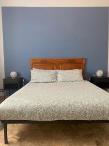 uma cama com uma cabeceira em madeira e uma parede azul em Casa ad Alba em Alba