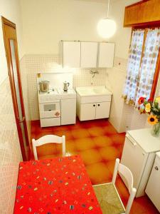 una pequeña cocina con mesa y una mesa roja sidx sidx sidx sidx sidx en Lignano Riviera, en Lignano Sabbiadoro
