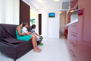 a woman and two children sitting on a couch at Internazionale - Family Village in Sottomarina