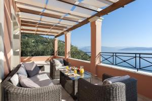 a patio with wicker chairs and a table on a balcony at Villa Kyma, Kaminaki Villas in Corfu With Private Pool And Spectacular Sea Views in Agní