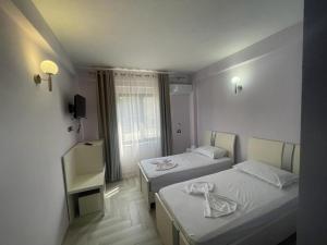 a hotel room with two beds and a window at Hotel Ferrara in Durrës