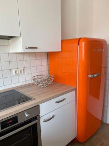 eine Küche mit einem orangefarbenen Kühlschrank in der Unterkunft Ferienwohnung mit 2 Zimmer im Belgischen Viertel in Köln