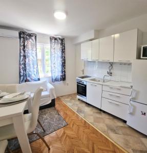 una cucina con armadi bianchi, tavolo e lavandino di APARTMENT LEA BAYVIEW a Dubrovnik