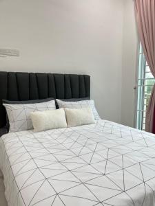a bedroom with a bed with a black and white comforter at Anjung Rindu Homestay (Kuala Terengganu, UMT, UniSZA) in Kuala Terengganu