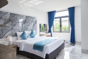 a bedroom with a large bed with blue curtains at Khang Thịnh Hotel Long Thành in Long Thành