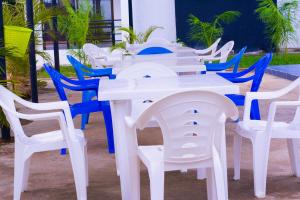 Volume view Apartments في مومباسا: مجموعة من الطاولات والكراسي البيضاء مع أشجار النخيل