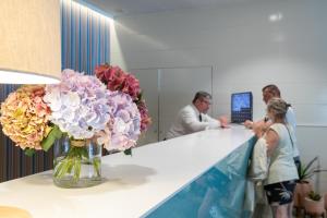 a woman standing at a counter with a vase of flowers at Prestige Goya Park in Roses +45 photos