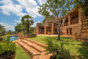 une maison en pierre avec un jardin et une piscine dans l'établissement Idwala Le Ingwe Lodge, à Hekpoort