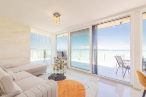 a living room with a white couch and a large window at LelleMarine by BLTN Apartmanok Balatonlelle in Balatonlelle