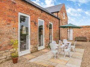a patio with a table and chairs and an umbrella at The Coach House in Ingoldsby