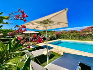 a white umbrella and chairs next to a swimming pool at Villa Azzurra in Monte Petrosu