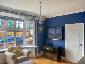 ein Wohnzimmer mit blauen Wänden, einem Stuhl und einem TV in der Unterkunft Two The Manor Born in Tynemouth