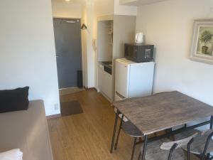 a small kitchen with a table and a refrigerator at Morinomiya Flat 森ノ宮フラット in Osaka
