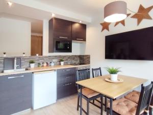 Mood Bilbao Apartamentos - New & Special في بلباو: مطبخ مع طاولة خشبية وغرفة طعام