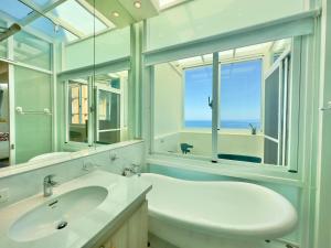 La salle de bains est pourvue d'un lavabo blanc et d'une fenêtre. dans l'établissement Go to Qixingtan Seaview B&B, à Dahan