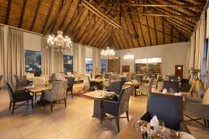 a dining room with tables and chairs and chandeliers at Safari Plains in Mabula