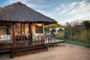 a hut with a bench and a table and chairs at Safari Plains in Mabula