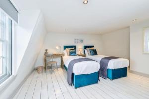 two beds in a white room with a desk and a table at Victorian townhouse - Stamford centre - 2 big bedrooms, living room kitchen etc tastefully decorated in Lincolnshire