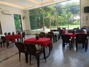 a restaurant with red tables and chairs and large windows at LUNAPIENA RESORTS in Tiruvankod