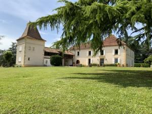 una casa grande con un gran patio con un árbol en La Téoulère du Bas, en Laguian-Mazoux