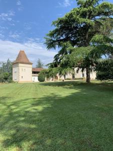 un gran edificio con un árbol en medio de un campo en La Téoulère du Bas, en Laguian-Mazoux