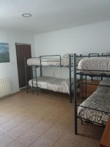 a room with three bunk beds and a tiled floor at Hostal El Desvío in Sierra Nevada
