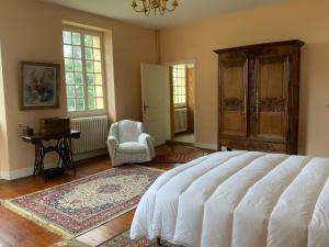 1 dormitorio con 1 cama blanca grande y 1 silla en La Téoulère du Bas, en Laguian-Mazoux