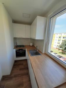 uma cozinha com armários brancos e uma grande janela em Apartament Leszczynki em Gdynia