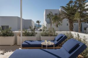 d'une terrasse avec 2 chaises bleues et une table. dans l'établissement Cosme, a Luxury Collection Resort, Paros, à Náoussa