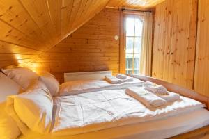 Una cama en una habitación de madera con toallas. en Bella Mura Nature Chalet I27 en Podčetrtek