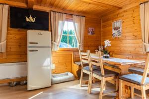 Il comprend une cuisine équipée d'un réfrigérateur, d'une table et de chaises. dans l'établissement Bella Mura Nature Chalet I27, à Podčetrtek